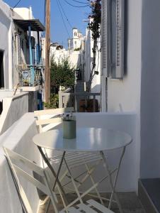 a white table and chairs on the side of a building at Holy Summer in Naousa Market Streets in Naousa