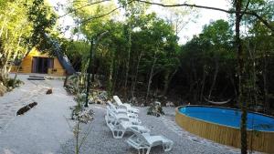 a row of white lounge chairs next to a swimming pool at Woodland Paradise Two charming wooden houses in the stone in Ljubuški