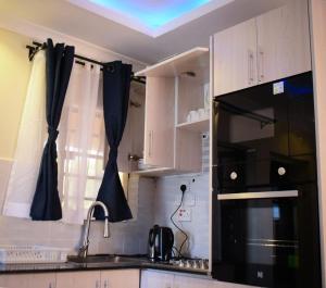 a kitchen with white cabinets and a black microwave at Golden Dream in Maseno
