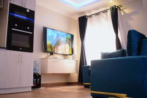 a living room with a tv and a blue chair at Golden Dream in Maseno
