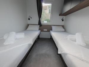 2 łóżka w małym pokoju z oknem w obiekcie Mobile Homes Camp Klenovica w mieście Klenovica +37 zdjęć