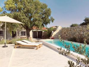 a swimming pool with two lounge chairs and an umbrella at Vasantina Kamena Kućica in Mala Čista
