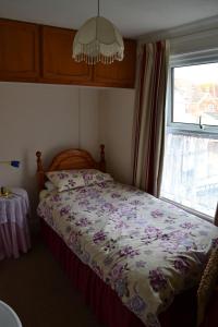 a bedroom with a bed with a floral comforter and a window at Knightsrest in Burnham on Sea