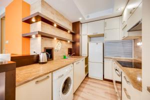 une cuisine avec des armoires blanches et une laveuse et une sécheuse dans l'établissement Orange by OneApartments, à Gdańsk
