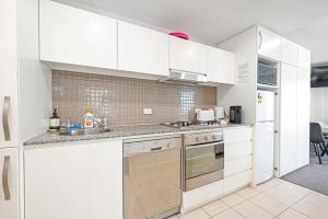 a kitchen with white cabinets and a sink at Beachfront Serenity Glenelg in Glenelg