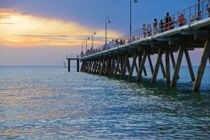 a group of people walking on a pier over the water at Beachfront Serenity Glenelg in Glenelg