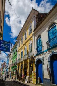un bâtiment jaune avec des portes bleues dans une rue dans l'établissement Casarão de Época no Coração do Pelourinho - Studio até 6 hóspedes, à Salvador