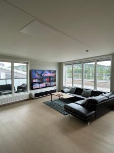 a living room with a black couch and a flat screen tv at Penthouse apartment - Lillestrøm in Lillestrøm
