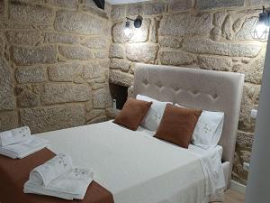 a bedroom with a bed in a stone wall at Vilar Rural Houses - Casa dos Avós in Tangil