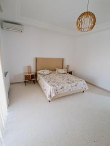 a bedroom with a bed in a white room at Duplex Marsa Ennessim in Dar el Ouzir