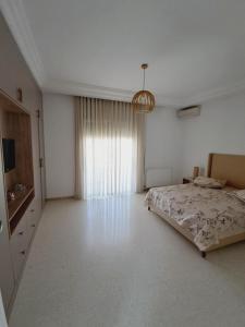 an empty bedroom with a bed and a chandelier at Duplex Marsa Ennessim in Dar el Ouzir