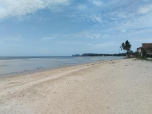 una playa de arena con una casa y una palmera en Ban Tai Bay Bungalows, en Ko Pha Ngan