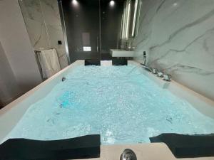 a large bath tub filled with blue water at Penthouse Manhattan jacuzzi balneo suite luxe in Toulouse +38 photos