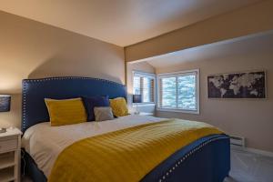 Un dormitorio con una cama azul con almohadas amarillas y una ventana en Creekside Condo 1335, en Sun Valley 16 fotos más