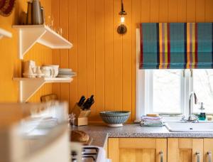 eine Küche mit gelben Wänden, einem Waschbecken und einem Fenster in der Unterkunft South Shore Cottage in Acharacle