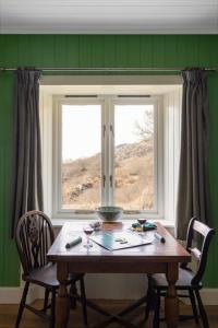 ein Tisch und Stühle vor einem Fenster in der Unterkunft South Shore Cottage in Acharacle