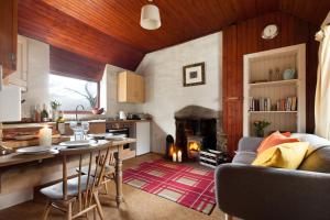 a kitchen and living room with a table and a fireplace at Sawmill Cottage in Acharacle