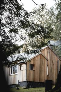 a wooden house with a tree in front of it at Timber Cottage in Acharacle +2 photos