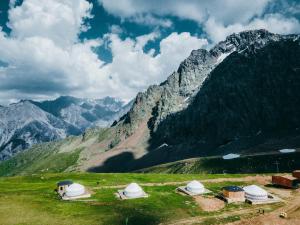 a group of tents on a mountain with mountains in the background at Yurta Base Camp, Shymbulak Mountain Resort in Besqaynar