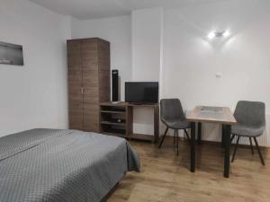 a bedroom with a bed and a table and a television at Domus in Ustka