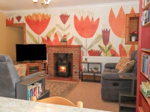 a living room with a fireplace and a tv at Hazel's Cottage in Campbeltown