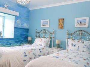 two beds in a bedroom with blue walls at Hazel's Cottage in Campbeltown