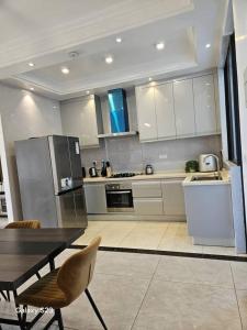 una cucina con armadi bianchi, tavolo e frigorifero di lovely 2 bed, 2.5 bath condo a Dar es Salaam