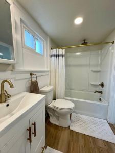 ein weißes Badezimmer mit einem WC, einer Badewanne und einem Waschbecken in der Unterkunft Wyoming Freedom in Casper + 20 Fotos
