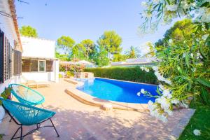 a swimming pool in a yard with a blue chair at Beautiful villa near the beach in Port de Pollensa