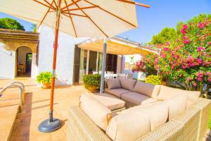 a patio with a couch and an umbrella at Beautiful villa near the beach in Port de Pollensa +32 photos