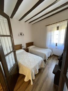 two beds in a room with wooden floors and windows at Casa rural hormilla in Hormilla
