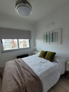 a white bedroom with a large bed with green pillows at Depto Zona Plaza Paso con opcion de Cochera byLofter in La Plata