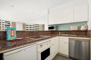 a kitchen with white cabinets and a sink at Amazing Sydney Apartment with Pool, Gym and Sauna in Sydney