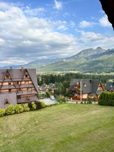un groupe de maisons avec des montagnes en arrière-plan dans l'établissement Z widokiem na Giewont, à Kościelisko