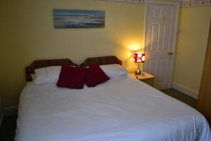a bedroom with a white bed with red pillows at Knightsrest in Burnham on Sea