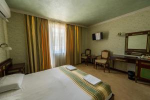 a hotel room with a bed and a desk and a mirror at Family Hotel Lazur in Kyustendil