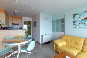a living room and kitchen with a yellow couch and a table at L'arc en ciel in Bray-Dunes