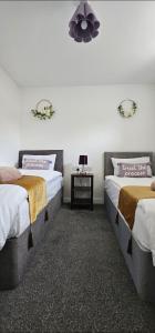 a bedroom with two beds and a table with a lamp at Deluxe Town Centre 2 Bedroom Apartment in Stevenage