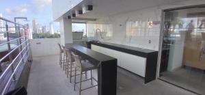 a kitchen with a black counter and some chairs at Flat 1305 Manaíra Apart Hotel - JP in João Pessoa