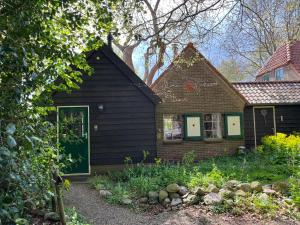 ArriënDoevelsteeg Ommen的一栋黑色的房子，有绿色的门和院子