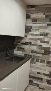 a kitchen with white cabinets and a tile wall at Cal Tu U in San Fausto de Campcentellas