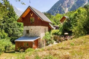 an old house on a hill with mountains in the background at Ecrins Lodge in Le Bourg-dʼOisans