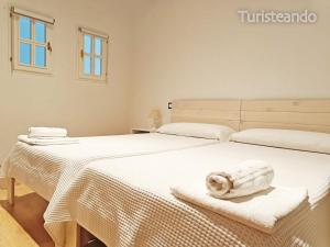 2 Betten in einem weißen Zimmer mit Handtüchern darauf in der Unterkunft Apartamento Llerandi 1C - Ideal para dos personas in San Vicente de la Barquera