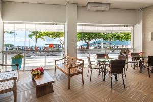 a dining room with tables and chairs and a view of the ocean at IPTZ160- Frente mar c/ vista incrível do 16º andar in Balneário Camboriú