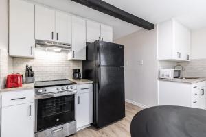 een keuken met een zwarte koelkast en witte kasten bij Calmont Guest House in Fort Worth