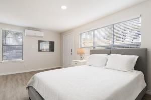 een witte slaapkamer met een bed en twee ramen bij Calmont Guest House in Fort Worth +4 foto's