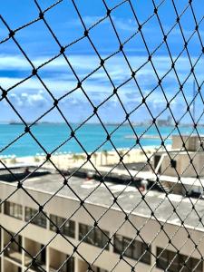 a view of the beach from a chain link fence at Flat Atlântico 405 in Fortaleza +5 photos