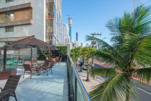 d'un balcon avec des tables, des chaises et un palmier. dans l'établissement ITNC091 - Incrível vista para o mar com 3Q+3WC, à Balneário Camboriú