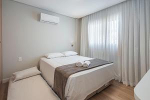 ein weißes Schlafzimmer mit einem Bett mit zwei Schuhen darauf in der Unterkunft LFYT135-Alto padrão localização ideal Av Atlântica in Balneário Camboriú