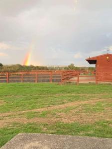 a rainbow in the sky over a field with a fence at Modern, Stylish lodge with Paddock Views in Sandwich